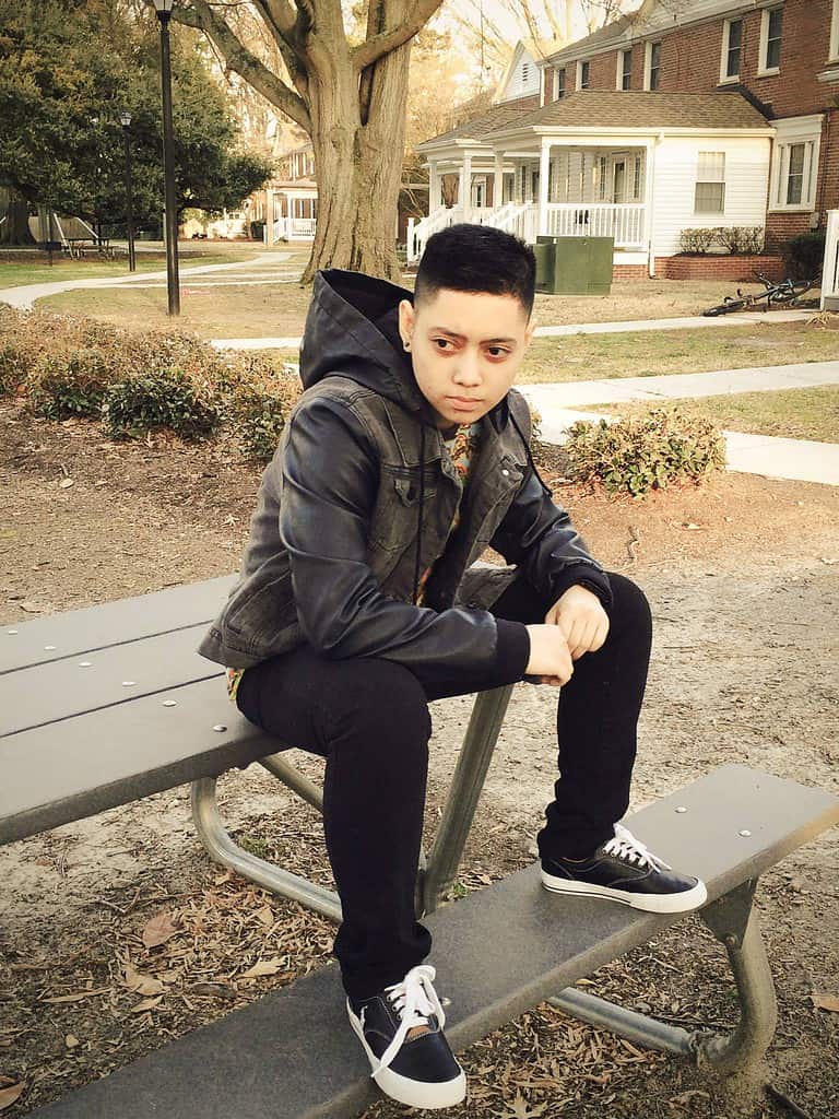 Person sitting on bench in a residential neighborhood.