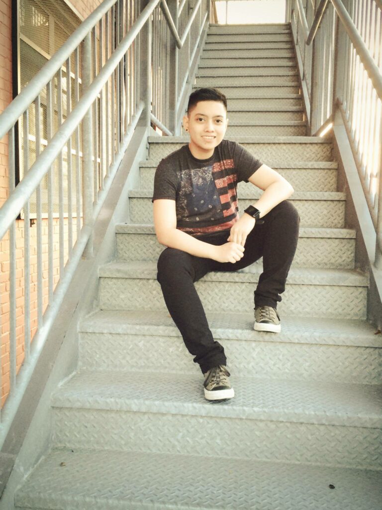 Person sitting on metal stairs outside building.
